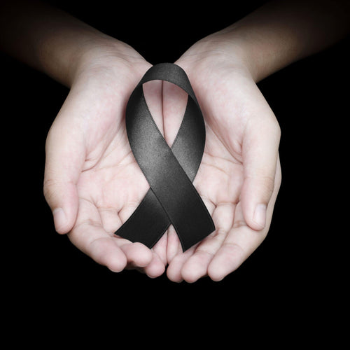 Black background. Womans hands cupped holding large black ribbon, for remembrance and mourning 