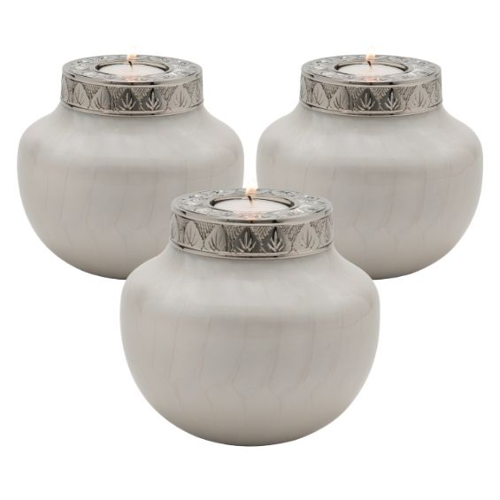 Set of three matching keepsake sharing urns for human ashes. 3 White & silver candle holder funeral urns with tealight candles. White metal urn body is pearlescent, like mother of pearl. Silver finish lid has a tea light recess and has intricate engraving